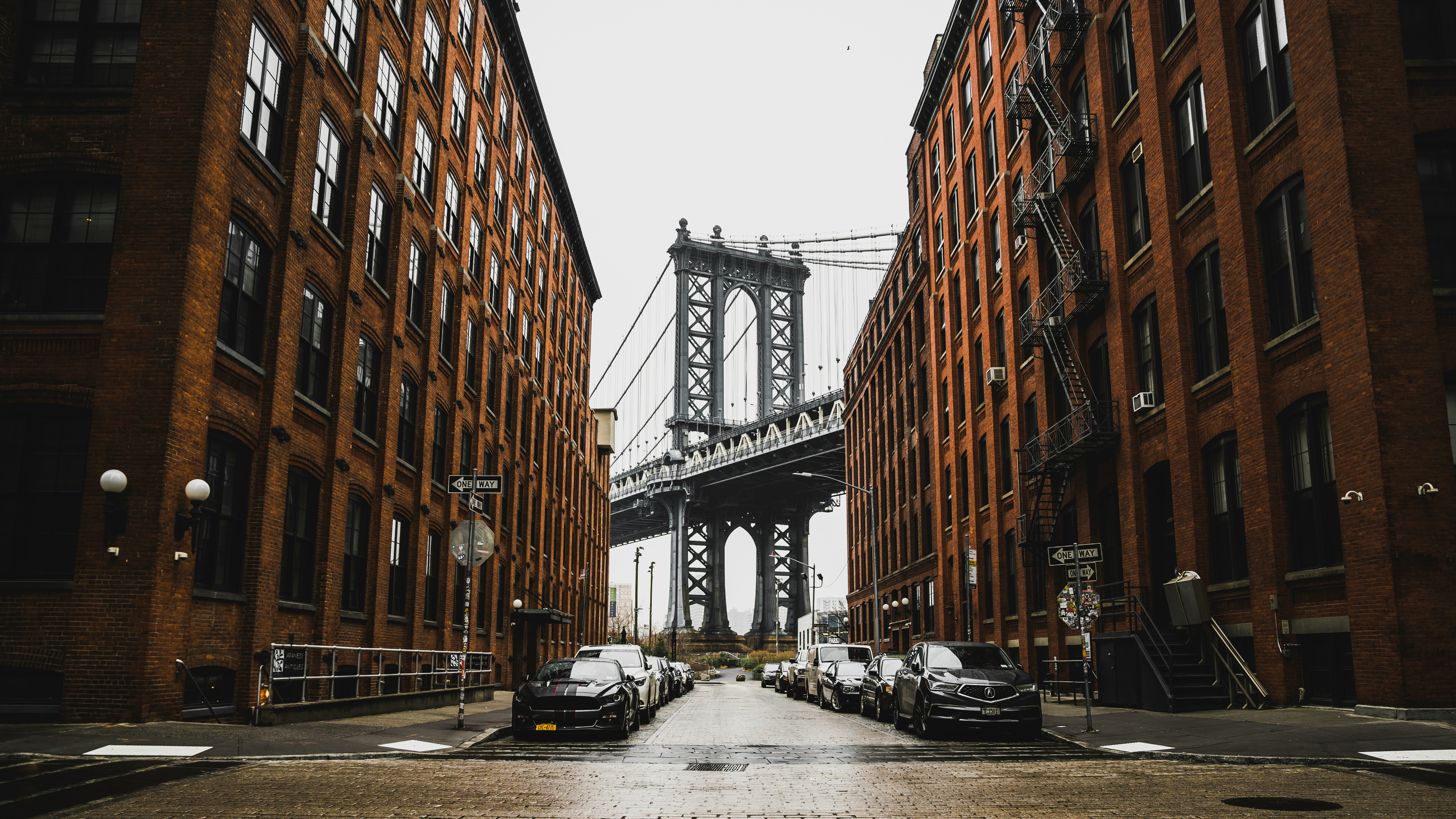 Washington Street in DUMBO, Brooklyn, framing the full Manhattan Bridge between red-brick loft buildings